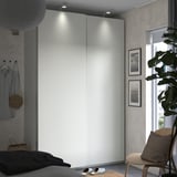 Moderner weißer Kleiderschrank mit Schiebetüren. Dekoriertes Schlafzimmer mit Pflanzen und Kunst.