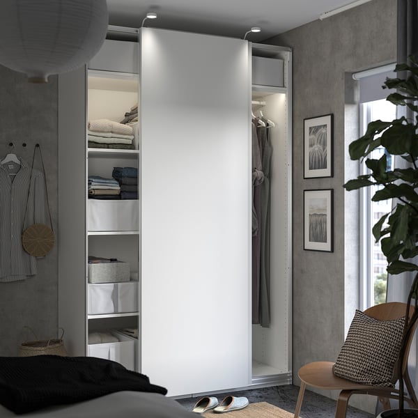 Modernes Schlafzimmer mit weißem Kleiderschrank, grauem Kopfteil, Holzstuhl und Pflanzen.