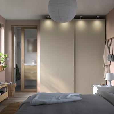 Modernes Schlafzimmer mit grauem Bett, großem Einbauschrank mit Schiebetüren und einer hohen Lampe.