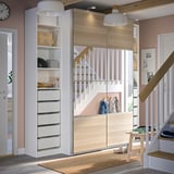 Moderner Eingangsbereich mit PAX-Kleiderschrank. Weiße Schubladen, helle Holztüren, Schiebetüren, sanfte Beleuchtung, rosa Wände, klares Design und Holzböden.