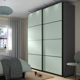 Modernes Schlafzimmer mit großem, hellem Schiebeschrank und Bett, begleitet von einem Fenster mit Vorhängen und einer Pendelleuchte.