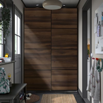 Großer hölzerner PAX-Garderobenraum , umgeben von kleineren Möbeln, mit modernen, dunklen Tönen und minimalistischem Design.