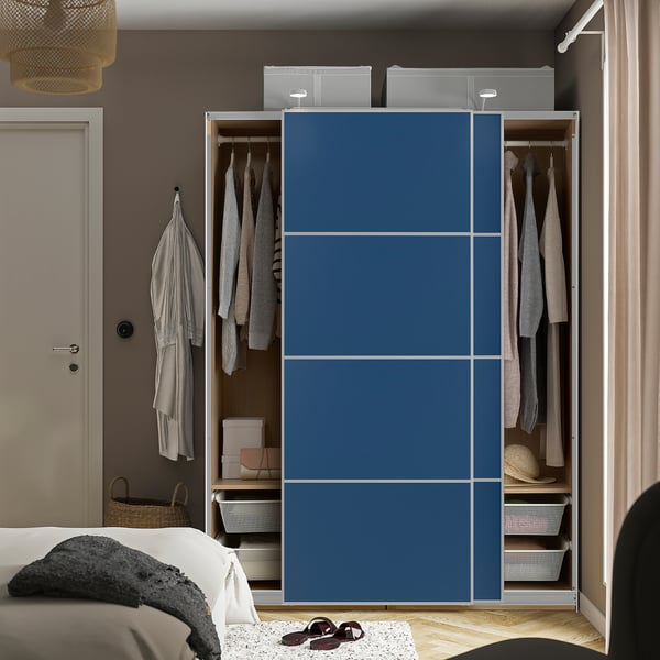 Schlafzimmer mit offenem Kleiderschrank mit Kleidung und Accessoires. Blaue Schiebetüren, Innenregale und helles Bett.