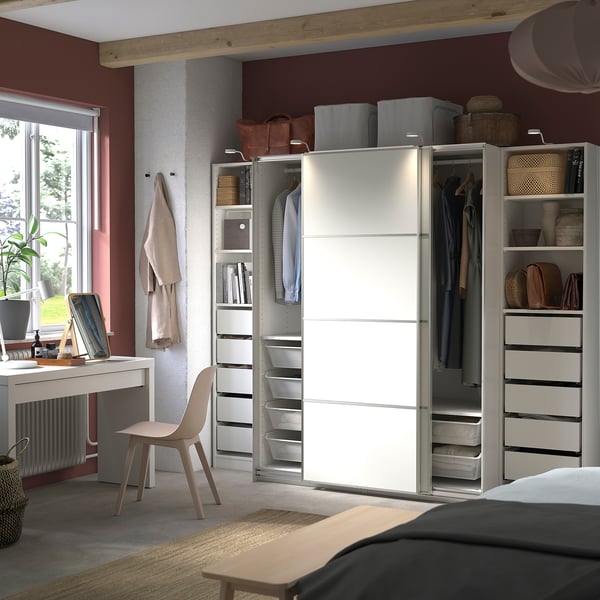Modernes Schlafzimmer ein weißer PAX-Kleiderschrank mit Schiebetüren, umgeben von organisierten Regalen und Schubladen.