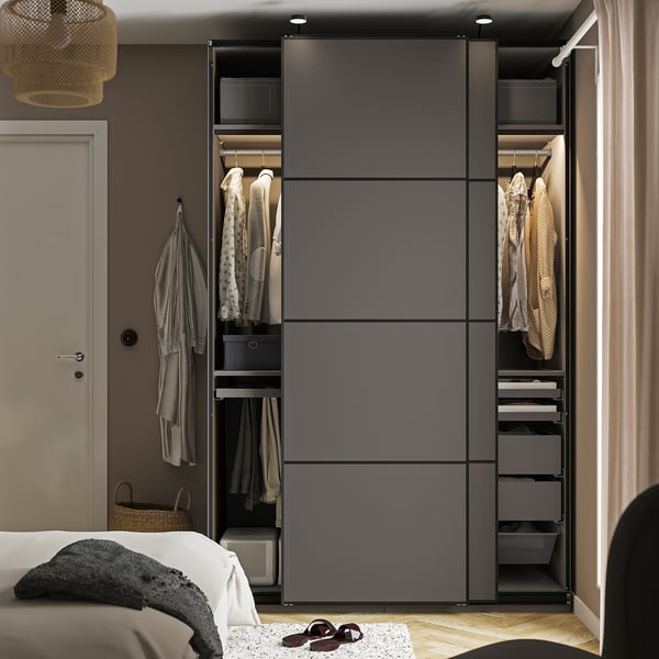 Ein modernes Schlafzimmer mit einem grauen PAX-Kleiderschrank und einem Bett, einer weißen Decke und Flip-Flops.