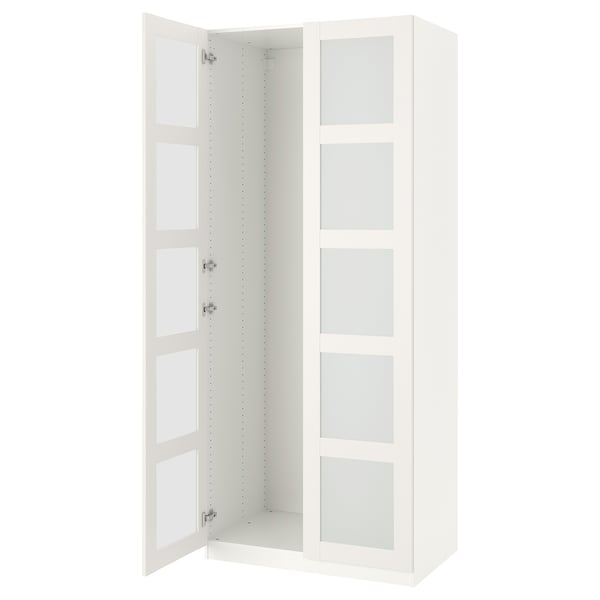 Ein offener weißer IKEA PAX-Kleiderschrank, hoch und rechteckig, mit Glastüren und Metallscharnieren.