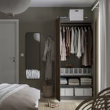 Modernes Schlafzimmer mit offenem Kleiderschrank, Kleiderbügeln, Aufbewahrungsboxen und Spiegel.