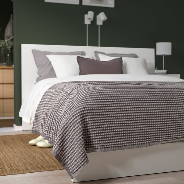 Greyscale PELARTUJA Tagesdecke auf dem Bett mit Kopfteil, Kissen, Hausschuhe auf Teppich, dunkelgrüne Wände, minimalistisches Dekor.