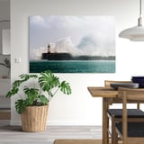 Ein modernes Wohnzimmer mit einem PJÄTTERYD-Leuchtturm-Leinwandbild, einer tropischen Pflanze und einer Pendelleuchte.