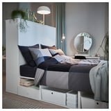 Modernes Schlafzimmer mit weißem PLATSA-Bett, grauer Bettwäsche, Nachttisch, Lampe und Spiegel.