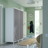 Moderner Eingangsbereich mit weißem Kleiderschrank, grauen Türen, hängenden Jacken und einer Uhr.