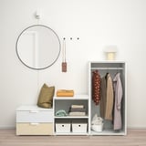 Minimalistischer Kleiderschrank-Organizer mit hängenden Mänteln, gefalteter Kleidung und einem runden Wandspiegel.