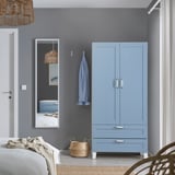 Modernes graublaues Schlafzimmer mit hohem PLATSA-Kleiderschrank, Weidenkorb und Spiegel.