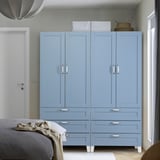 Schlafzimmer mit großem blauen PLATSA-Kleiderschrank mit Schubladen. Helles, luftiges Design mit weißen Beinen, neben Teilbett.