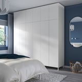 Schlafzimmer mit hohem weißem PLATSA-Kleiderschrank, minimalistischem Dekor und gemütlicher Bettwäsche.