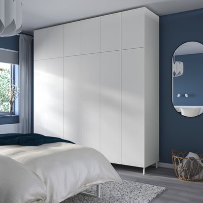 Schlafzimmer mit hohem weißem PLATSA-Kleiderschrank, minimalistischem Dekor und gemütlicher Bettwäsche.