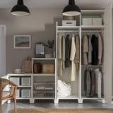 Ein moderner Kleiderschrank mit einer Kleiderstange und Regalen mit Körben und einem Spiegel, gut organisiert mit verschiedenen Kleidungsstücken und Accessoires.