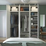 Offener Schlafzimmerschrank mit Kleiderbügeln, Regalen mit gefalteter Kleidung, Taschen und Aufbewahrungsbehältern. Organisiert mit verstellbaren Innenorganisationen.