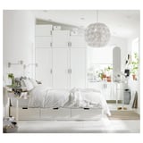Modernes weißes Schlafzimmer mit eleganten PLATSA-Aufbewahrungseinheiten, einem Bett mit frischer weißer Bettwäsche, stilvoller Beleuchtung und Pflanzen.