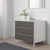 PLATSA Kommode mit 3 Schubladen, schlank und kompakt, mit Pflanze und Büchern.