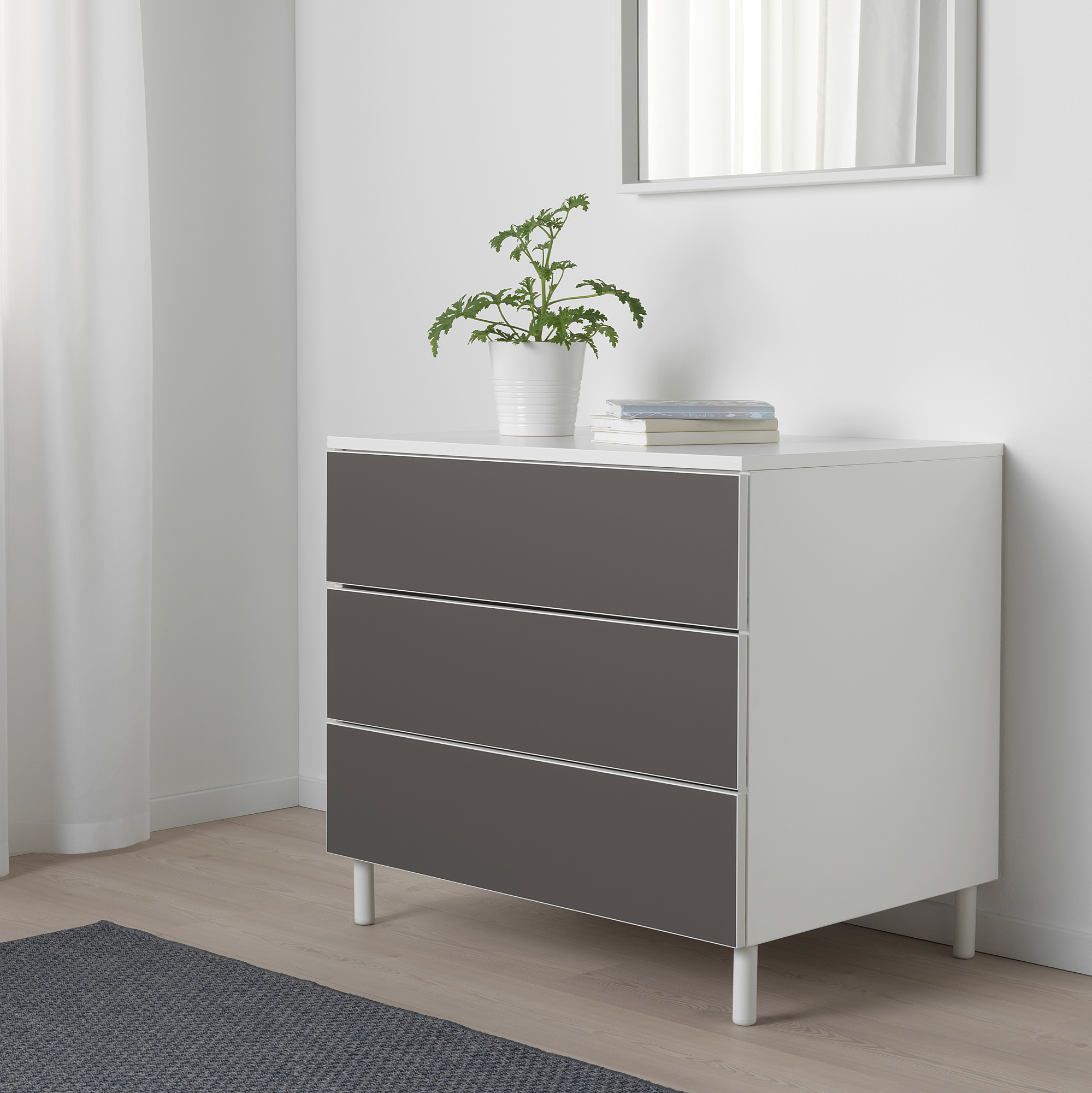PLATSA Kommode mit 3 Schubladen, schlank und kompakt, mit Pflanze und Büchern.