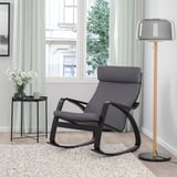 Modernes Wohnzimmer mit schwarzem POÄNG Schaukelstuhl, Holzlampe, grauen Vorhängen und Blumen.