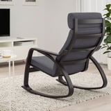 Modernes Wohnzimmer mit schwarzem POÄNG Schaukelstuhl auf weichem Teppich, neben kleinem Tisch mit Kaffeetasse.