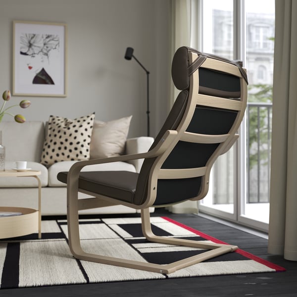 Modernes Wohnzimmer mit POÄNG-Liegestuhl, weißem Sofa, einfarbigem Teppich und großem Fenster mit Blick nach draußen.