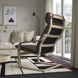 Modernes Wohnzimmer mit POÄNG-Liegestuhl, weißem Sofa, einfarbigem Teppich und großem Fenster mit Blick nach draußen.