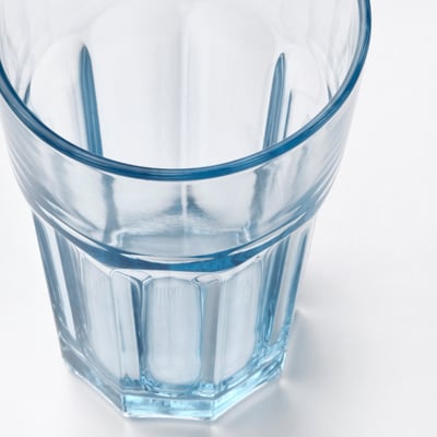 Klarer, blau getönter Becher aus gehärtetem Glas mit klassischem geriffeltem Design, der allein steht.