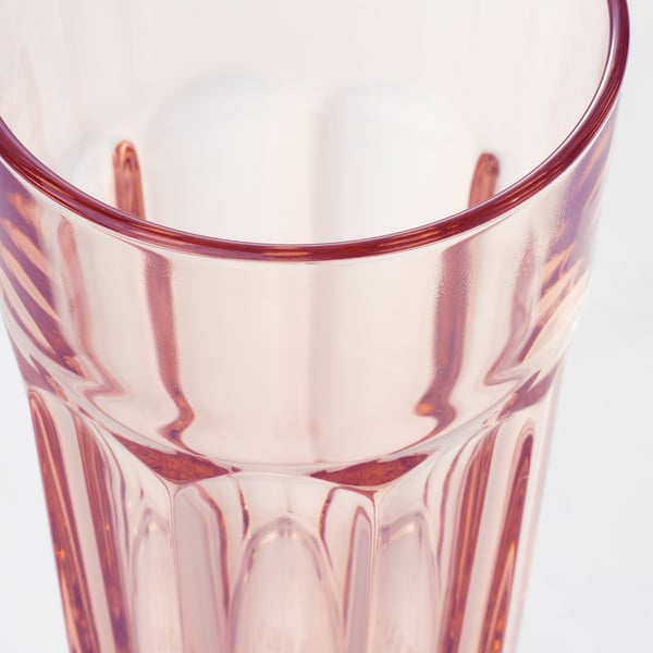 Eine Nahaufnahme eines rosafarbenen, durchscheinenden Glasbechers mit strukturierter Oberfläche und glattem Rand, der seine Langlebigkeit und sein stilvolles Design hervorhebt.