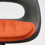 Nahaufnahme eines modernen Sitzkissens auf einem Stuhl. Leuchtend orangefarbener, weicher Stoff mit rutschfester Unterseite, der Qualität und Komfort zeigt.