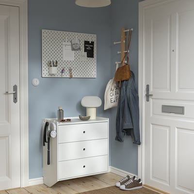 Blaues Zimmer mit weißen RACKNÄS-Schubladen, Steckbrett und Schuhablage.