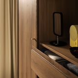 Holzschrank mit Schiebetür, goldenem Griff, schwarzer Lampe und gelbem Lautsprecher.