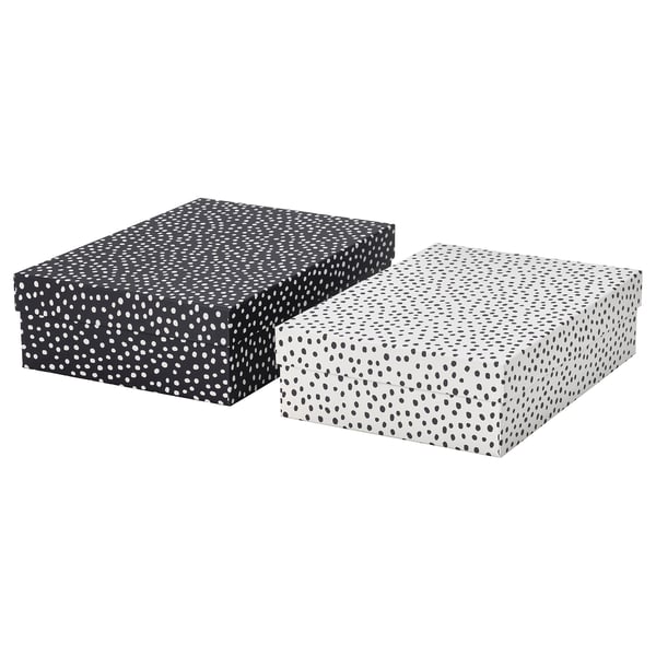Zwei rechteckige Aufbewahrungsboxen, eine schwarze und eine weiße, beide mit gepunkteten Mustern. Hergestellt aus recyceltem Karton. Ideal zum Organisieren von Schreibtischartikeln.