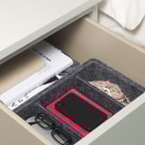 Offene Schublade mit Filztabletts zum Organisieren von Gläsern, Telefon, Buch und Schmuck.