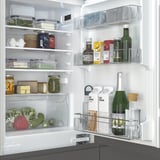 Gut organisierte Kühlschrankregale mit verstellbaren Fächern, durchsichtigen Behältern und verschiedenen Lebensmitteln. Inklusive Glasböden und LED-Beleuchtung.