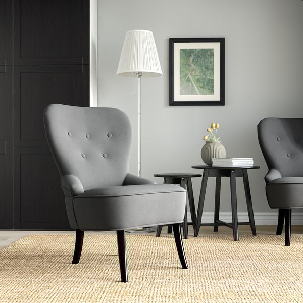 Moderner Wohnraum mit grauen Sesseln, Holzhockern, Lampe und Foto. Stühle traditionelles Design, Größe klein im Verhältnis zu Hockern.