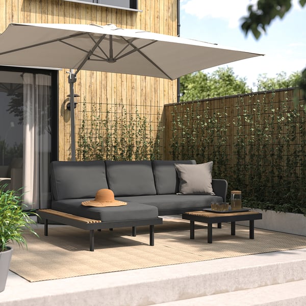 Moderne Terrassengarnitur: L-förmiges graues Sofa, Couchtisch, großer Sonnenschirm, Holzzaun, Pflanzen.