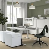 Modernes Homeoffice mit elektrischem Schreibtisch, Monitor, Stuhl und Dekor.