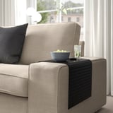 Sofa mit beigefarbener Polsterung und Armlehnenablage mit Schale und Getränk. Tablett klappbar, passend für verschiedene Armlehnenbreiten.
