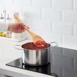 Kochen Sie gerührte rote Soße auf einem modernen Herd.