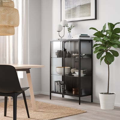 Modernes Wohnzimmer mit RUDSTA-Schrank, Pflanze, Essbereich und minimalistischem Dekor.