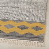 Flachgewebter Wollteppich mit komplizierten geometrischen Mustern. Gelber und grauer Zickzackstreifen, umrandet von Kelim-Motiv. Natürliche Fransen an den Rändern.