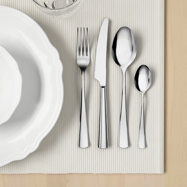 Ein ordentlich arrangiertes Set aus poliertem Besteck auf einem Tischset, bestehend aus Gabel, Messer, Löffel und Teelöffel, ideal zum Essen.