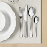 Ein ordentlich arrangiertes Set aus poliertem Besteck auf einem Tischset, bestehend aus Gabel, Messer, Löffel und Teelöffel, ideal zum Essen.