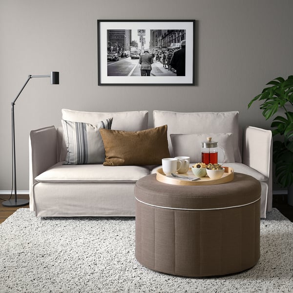 Großes L-förmiges Sofa mit brauner Ottomane, Kissen, Stehlampe und Wandkunst; Minimalistisches Design.