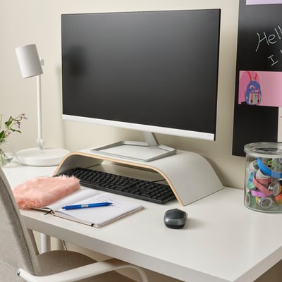 Weißer Monitorständer hebt den Bildschirm an, unterstützt die Tastatur und bietet Stauraum. Bunte Accessoires verbessern den Komfort und die Organisation.