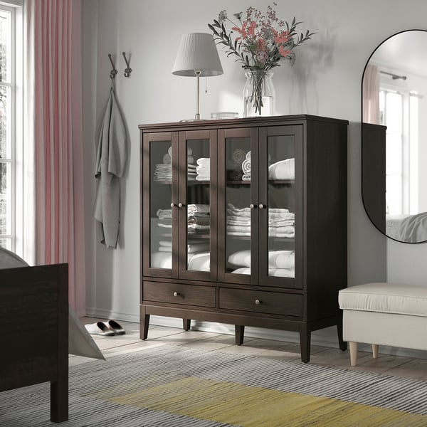 Gemütliches Schlafzimmer mit SJÖTÅTEL-Schrank, Bettwäsche, Lampe, Blumen, gestreiftem Teppich, Spiegel, Bett. Teppich grau mit gelben Akzenten.