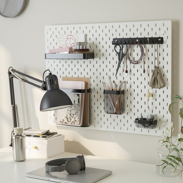 Schreibtisch mit SKÅDIS-Stecktafel mit Büchern, Stiften und Lampe. Enthält Haken, Behälter und Regale für eine organisierte Aufbewahrung.